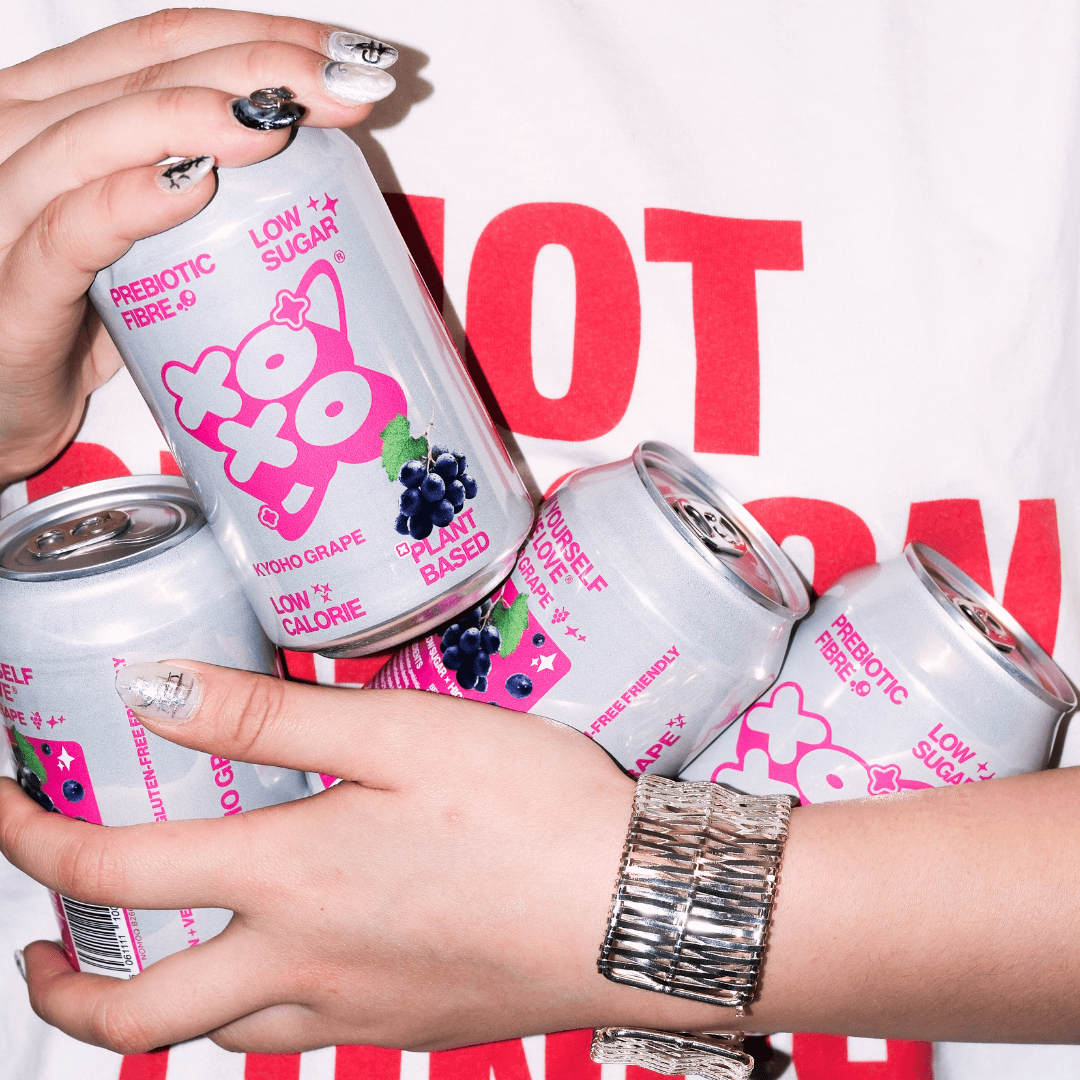 Kyoho Grape Prebiotic Soda | XOXO Limited Edition - 12 Pack in hands, showcasing bold flavors and plant-based goodness.