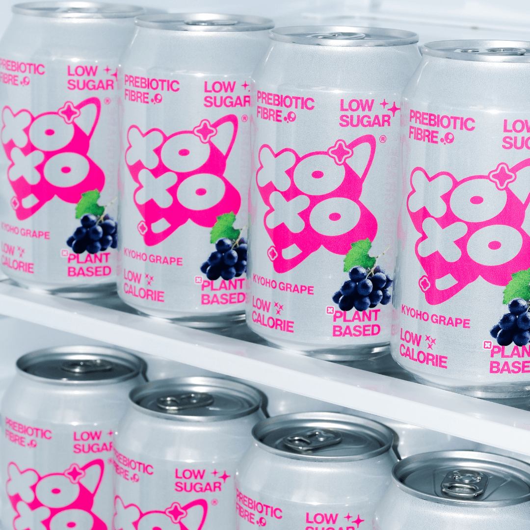 Kyoho Grape Prebiotic Soda | XOXO Limited Edition - 12 Pack in a fridge showcasing vibrant cans.